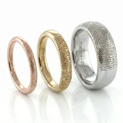 Three fingerprint rings in 9 carat rose gold 9 carat yellow gold and non carat white gold the fingerprint is featured on the outside of each ring